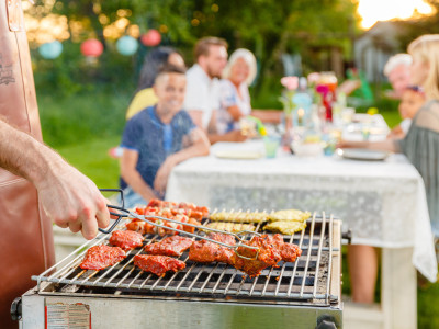 Vlees op de barbecue met familie aan tafel op de achtergrond